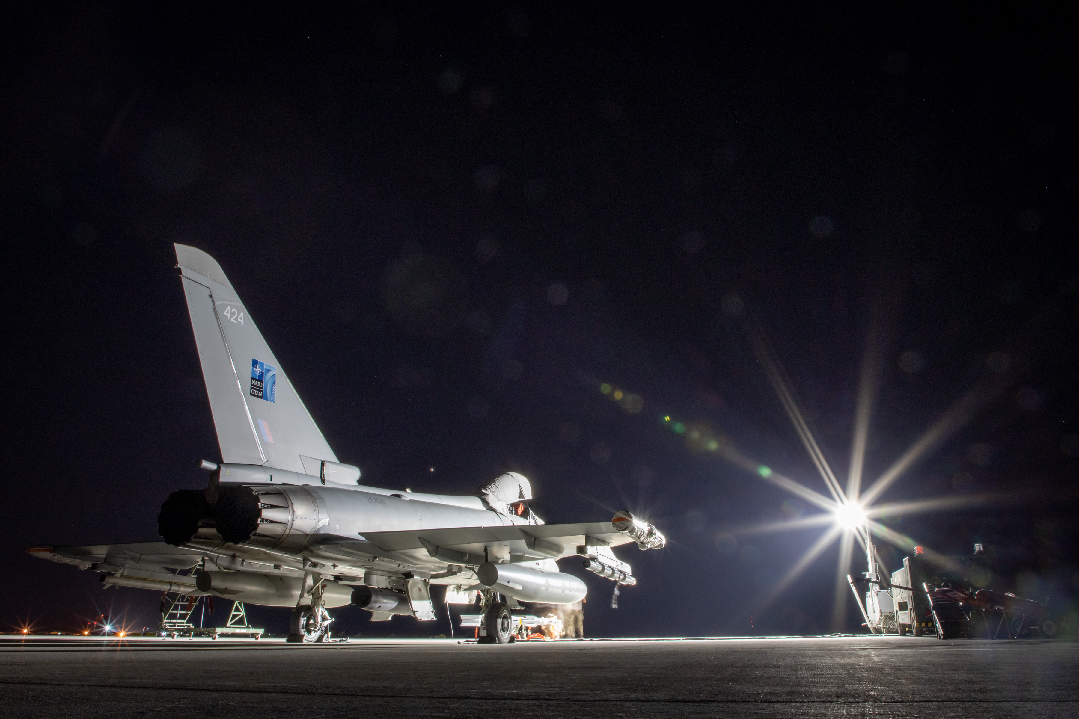 Jet aircraft on the airfield at night, strobe light casts rays.